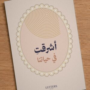 بطاقة إهداء بمقاس A5 عليها رسمة دوائر شمس مشرقة على خلفية خوخية وعبارة «أشرقتِ في حياتنا»، على طاولة خشبية